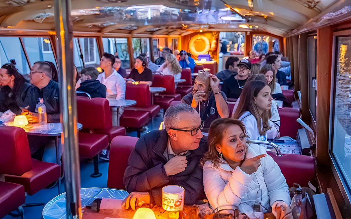 Evening canal cruise in Amsterdam with passengers enjoying the view.