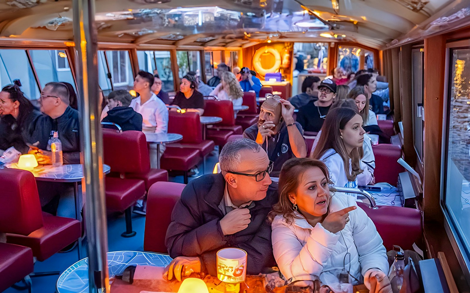 Amsterdam canal cruise boat on water during evening with city lights reflecting.