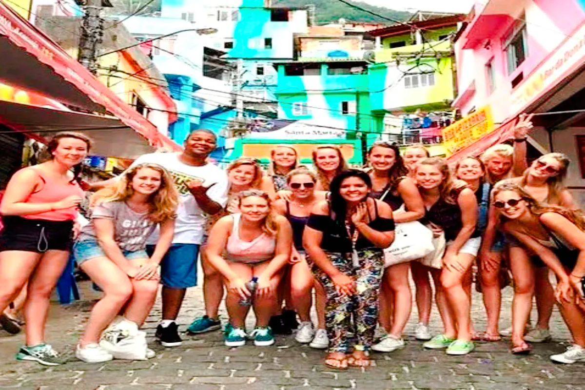 Group of tourists in Rocinha Favela, Rio de Janeiro, with colorful buildings in the background.