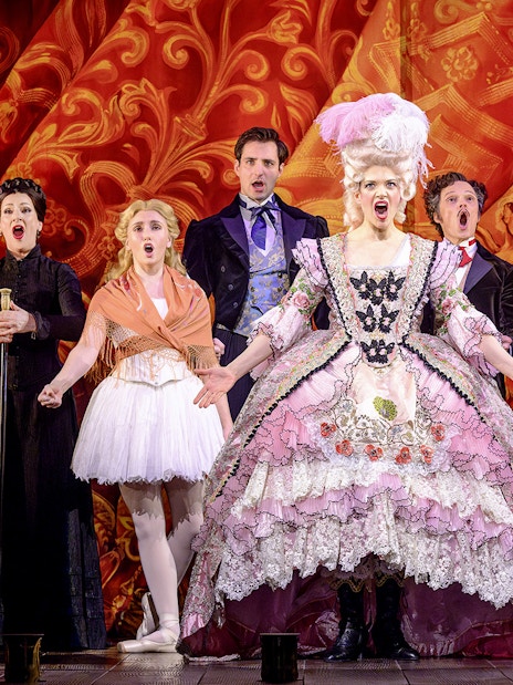 Cast performing in The Phantom of the Opera musical in Vienna, vibrant costumes and dramatic backdrop.
