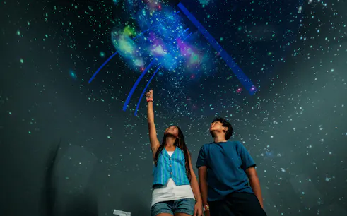 Visitors exploring a starry projection at Trans Studio Bali.