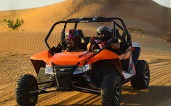 Desert buggy with two riders navigating sand dunes on a 4-seater safari adventure.