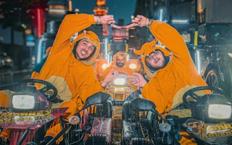 Go-kart riders in orange costumes at Shibuya Crossing, Tokyo Tower visible in background.