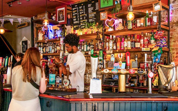 Bar scene in Soho, London with bartender serving drinks during the Twilight Soho Food & Drinks Tour.