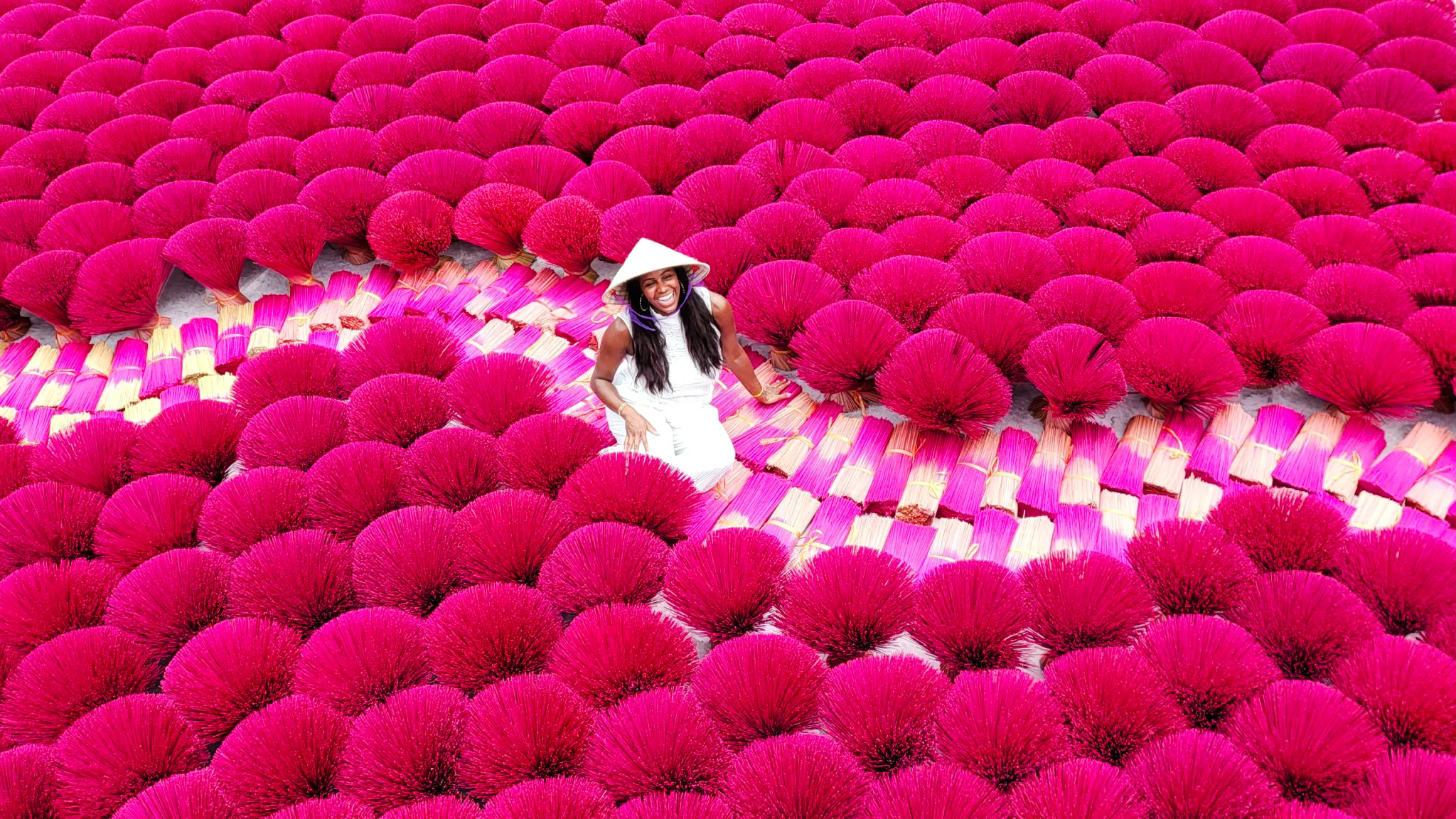 Incense drying at Quang Phu Cau Village, Hanoi, with a visitor among vibrant bundles.
