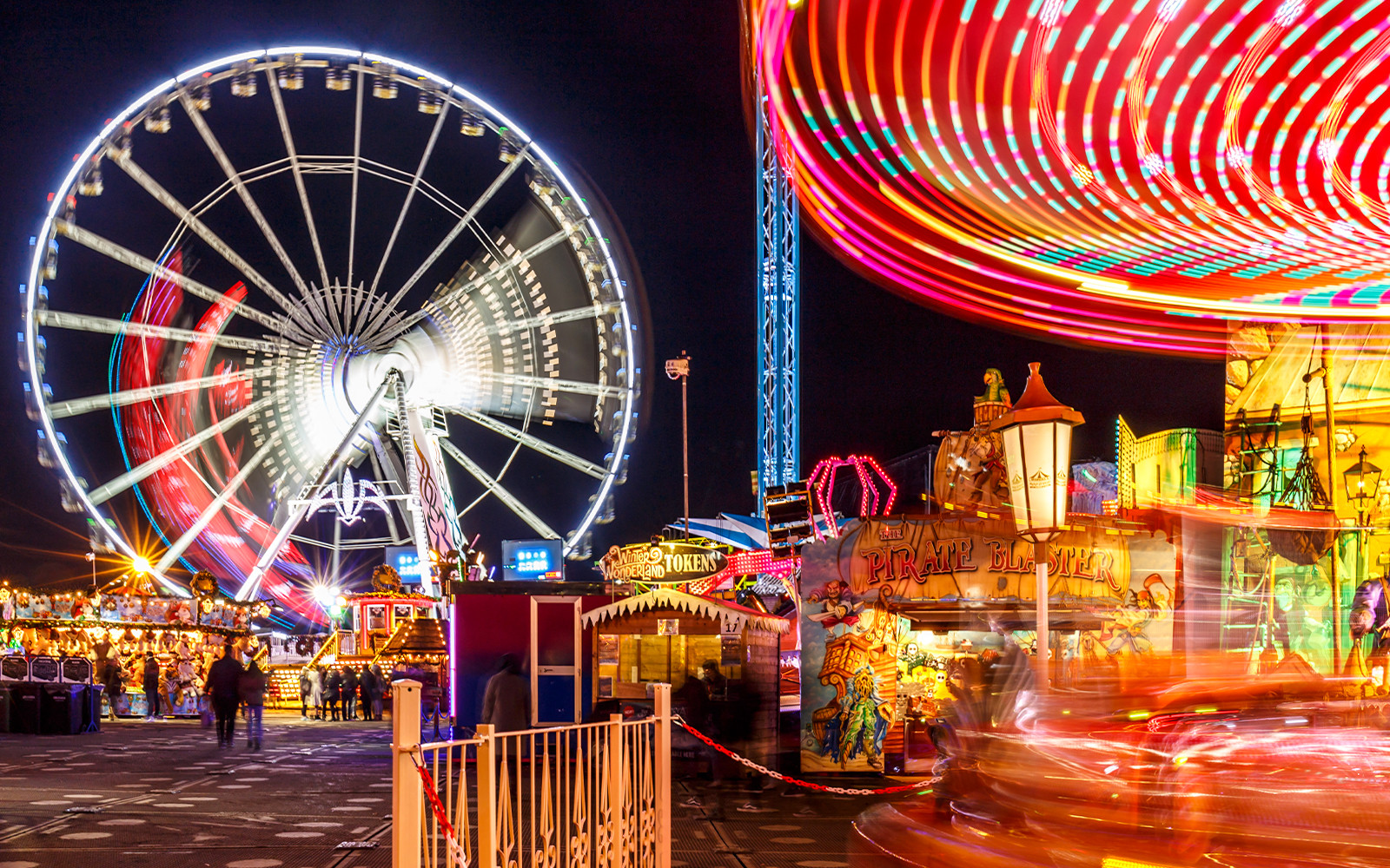 Ferris wheel and colorful rides at Winter Wonderland festival at night.