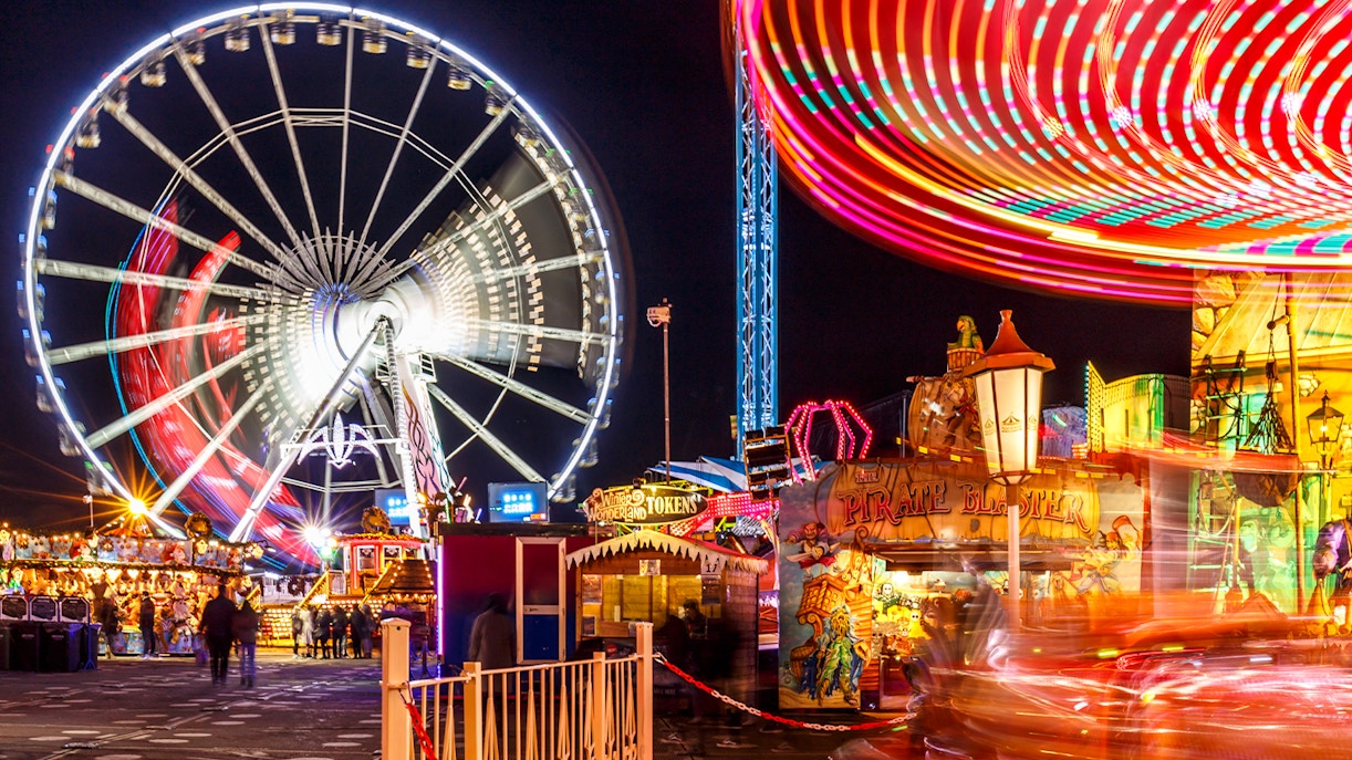 Ferris wheel and colorful rides at Winter Wonderland festival at night.
