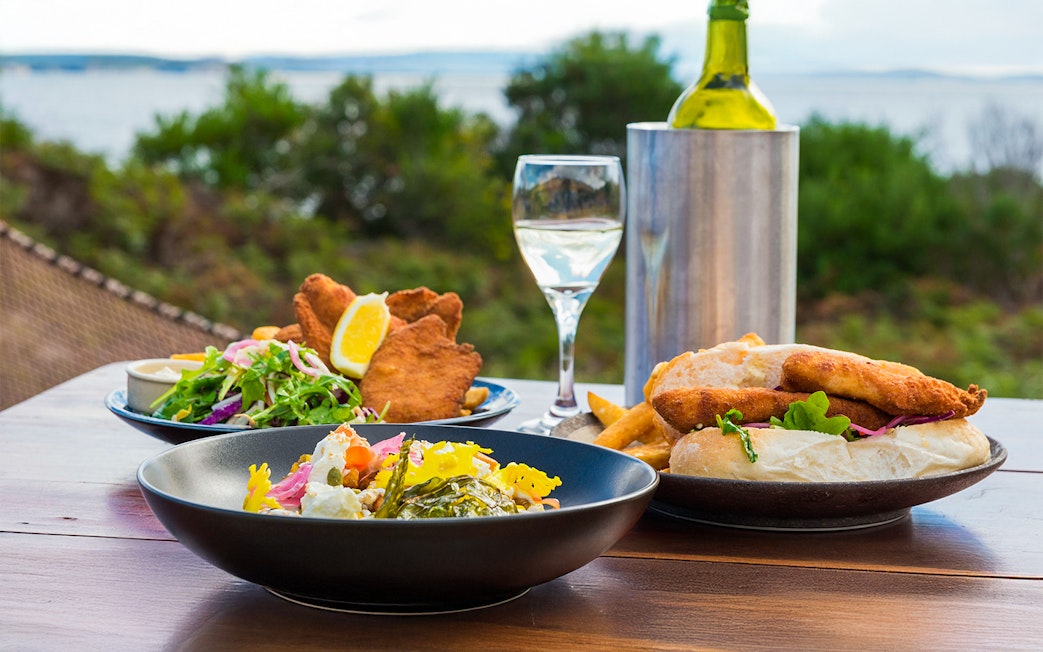 Outdoor dining with seafood and salad on Bruny Island, overlooking the coastline.