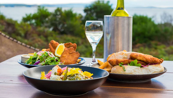 Outdoor dining with seafood and salad on Bruny Island, overlooking the coastline.