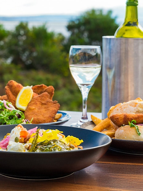 Outdoor dining with seafood and salad on Bruny Island, overlooking the coastline.