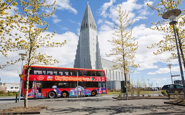 Red double-decker bus in front of Hallgrímskirkja church, Reykjavik Hop-on Hop-off City Tour.
