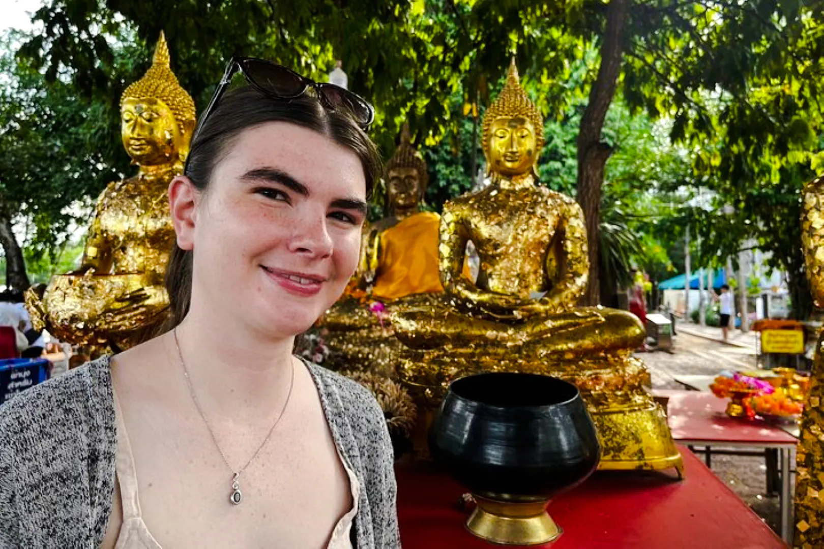 Visitor at Amphawa Floating Market with golden Buddha statues, Pattaya shore excursion.