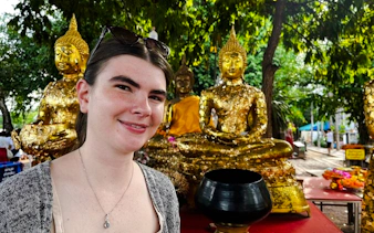 Visitor at Amphawa Floating Market with golden Buddha statues, Pattaya shore excursion.