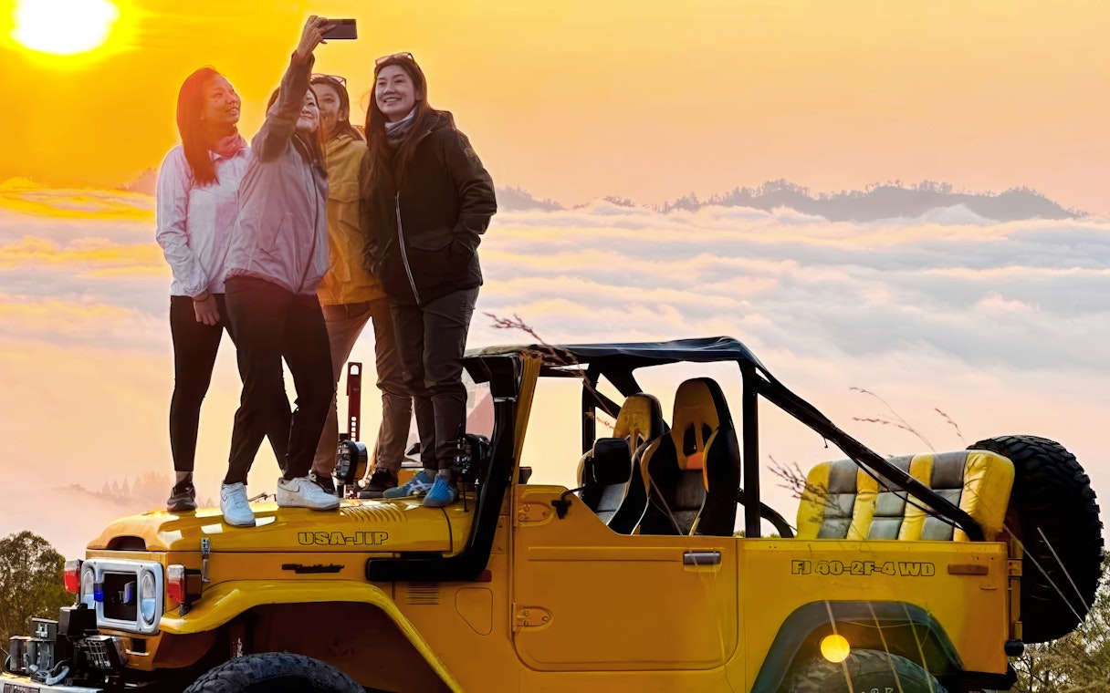 Tourists taking a selfie on a yellow jeep during a Black Lava Exploration in Bali at sunrise.