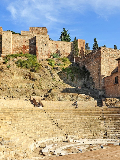 Roman Theater and Alcazaba in Málaga, Spain, with ancient stone seating and fortress walls.