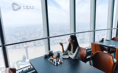 Woman enjoying dessert at Sky Café, 119th floor, Shanghai Tower with city view.