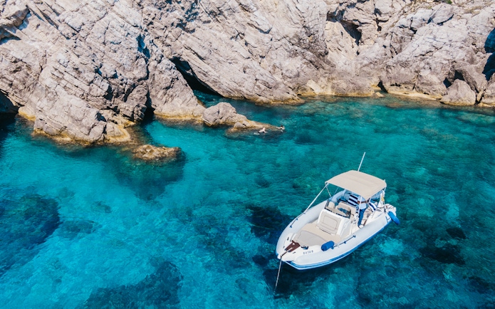 Private boat near rocky shore in Dubrovnik's Blue Cave, Croatia.