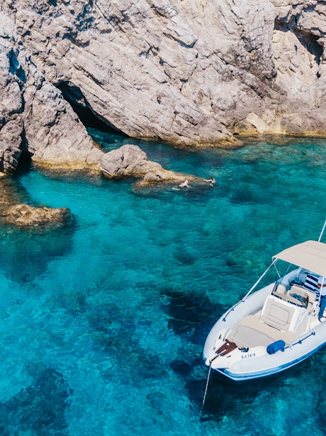 Private boat near rocky shore in Dubrovnik's Blue Cave, Croatia.