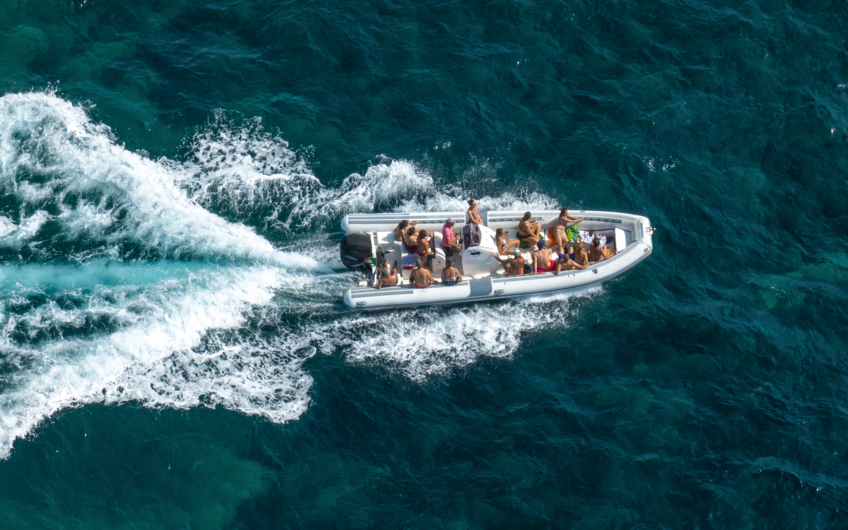Aerial view of a dinghy with passengers cruising on open water.