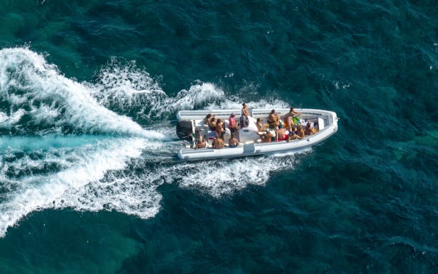 Aerial view of a dinghy with passengers cruising on open water.