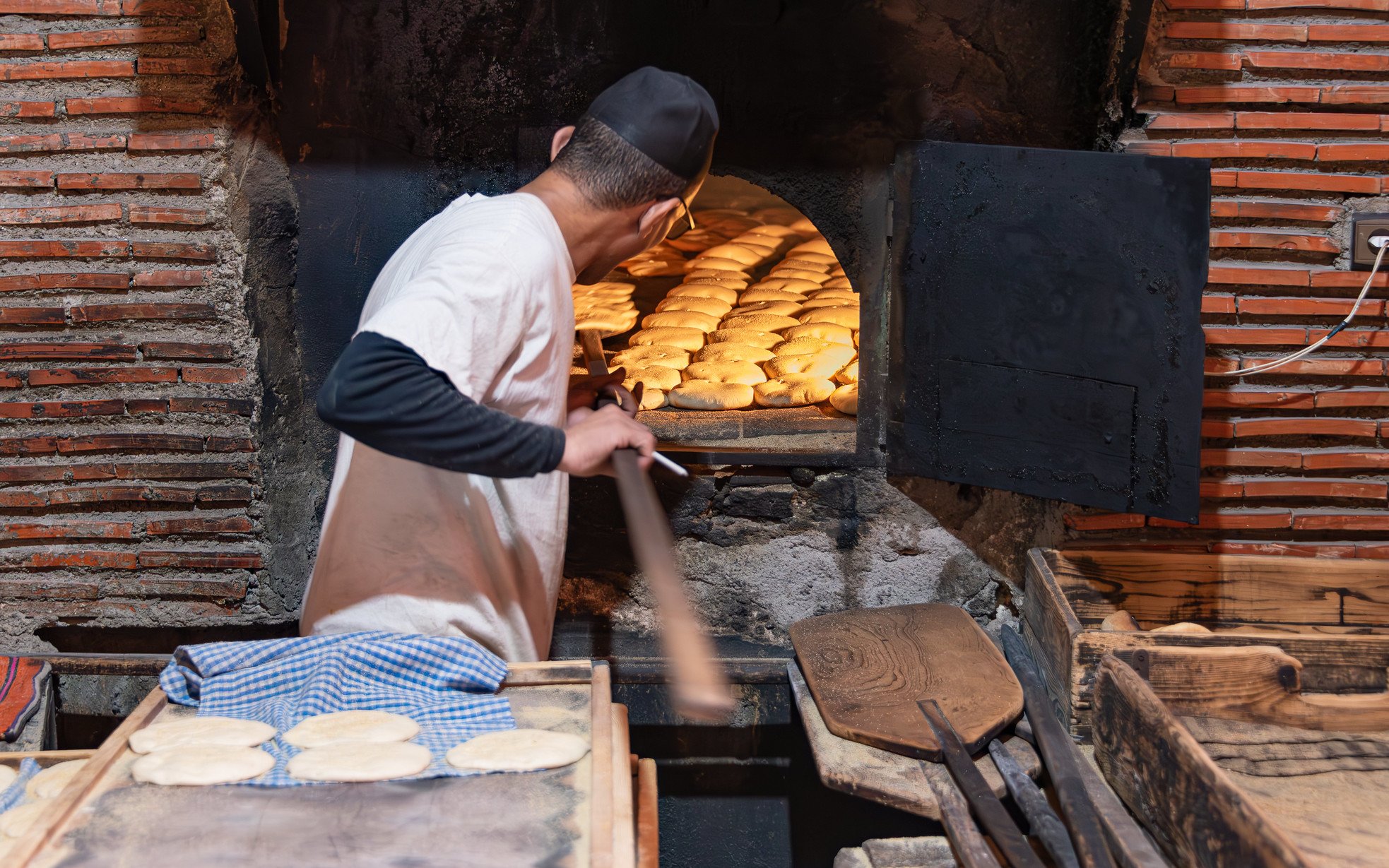 Baker placing bread in traditional oven, Marrakech souks tour.