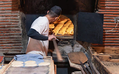Baker placing bread in traditional oven, Marrakech souks tour.