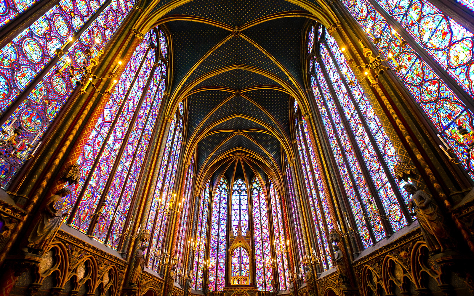View of the stunning Sainte Chapelle with ceiling, stained glass, floor and the altar.