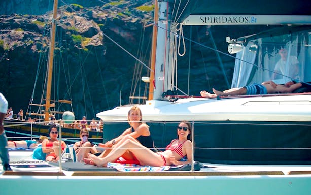 Guests sunbathing on a catamaran during Santorini cruise tour.