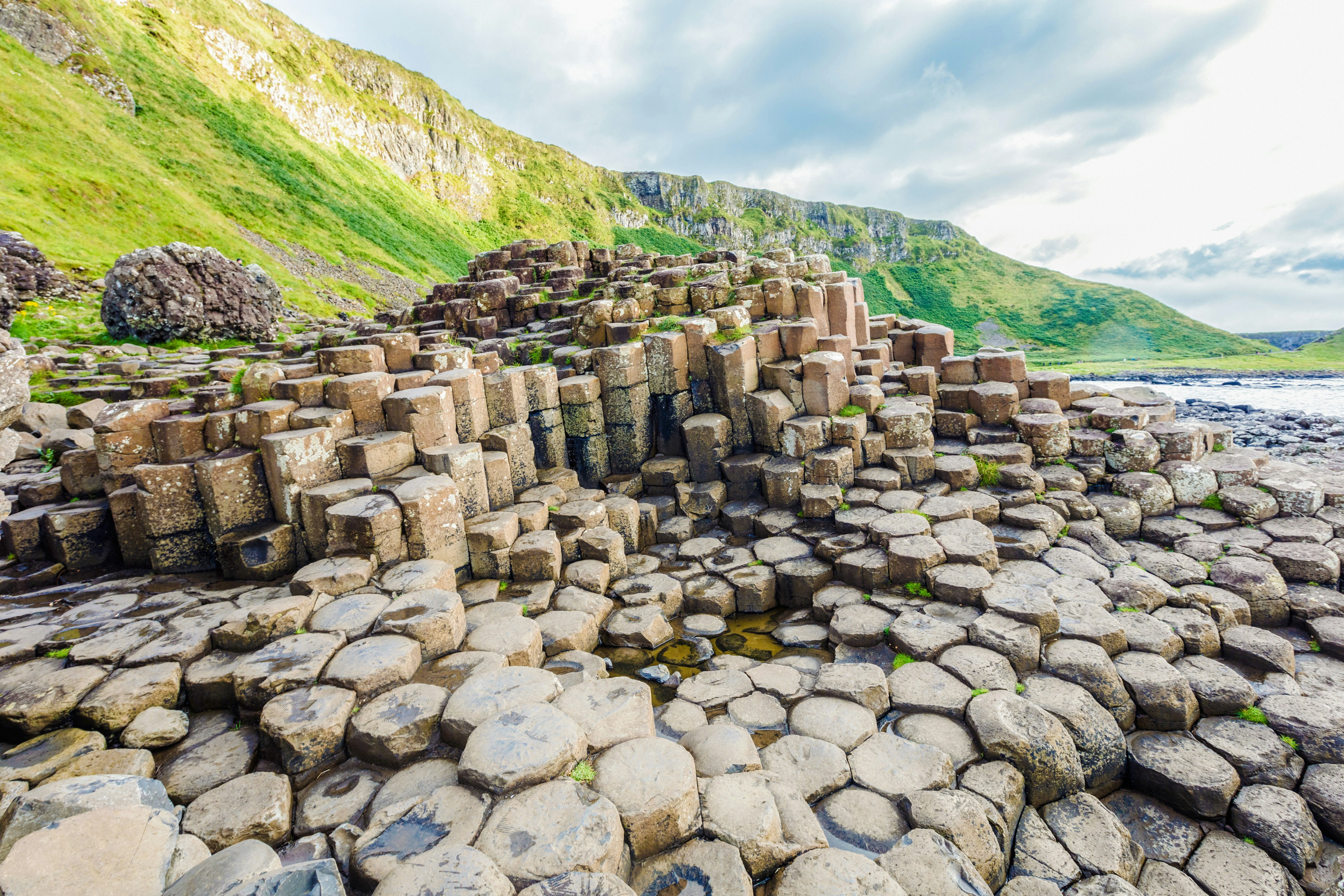 Giant's Causeway basalt columns with green cliffs in Northern Ireland.