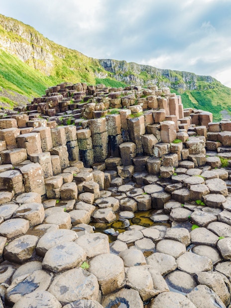 Giant's Causeway basalt columns with green cliffs in Northern Ireland.