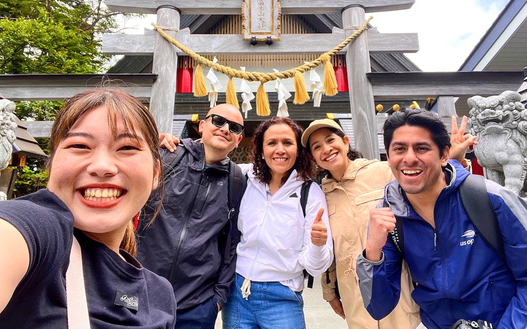 Group of tourists smiling in front of a shrine on the Fantastic Fuji & Hakone 1-Day Bus Tour.