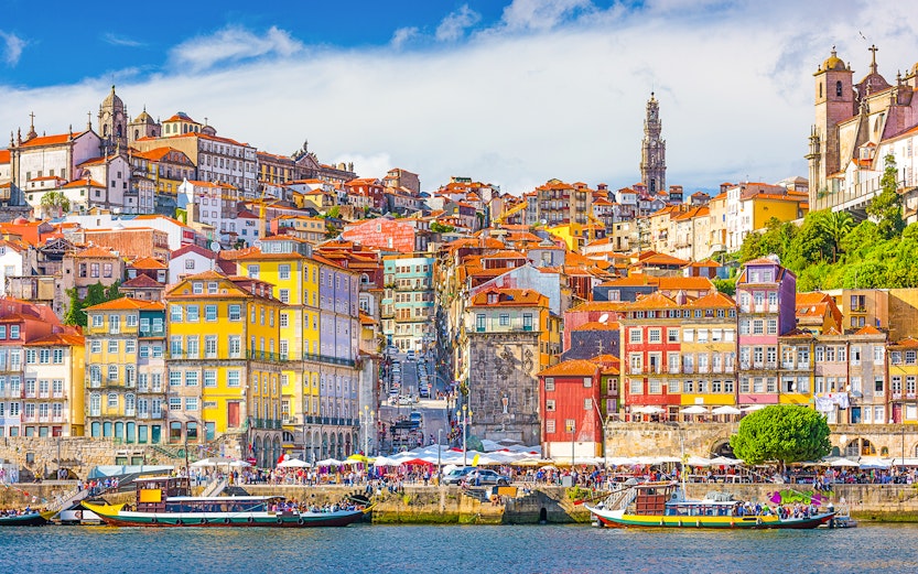 Colorful buildings along the Douro River in Porto, Portugal, with boats in the foreground.