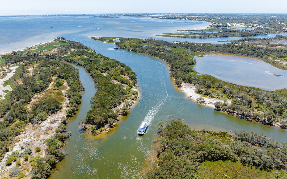 Aerial view of a boat cruising along the Murray River surrounded by lush greenery.
