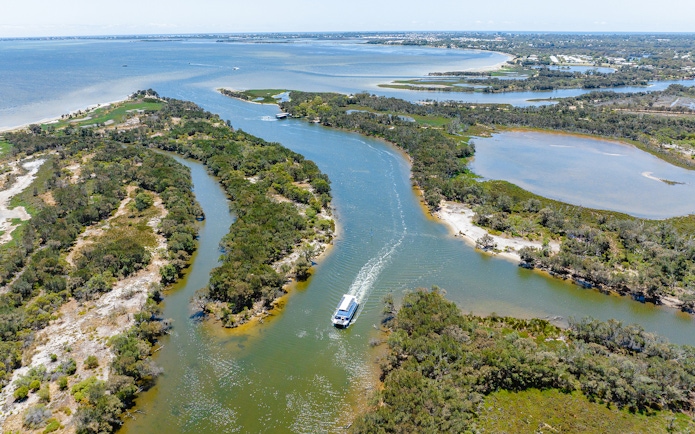 Aerial view of a boat cruising along the Murray River surrounded by lush greenery.