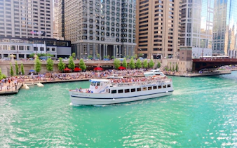 Chicago River cruise boat passing downtown skyscrapers.