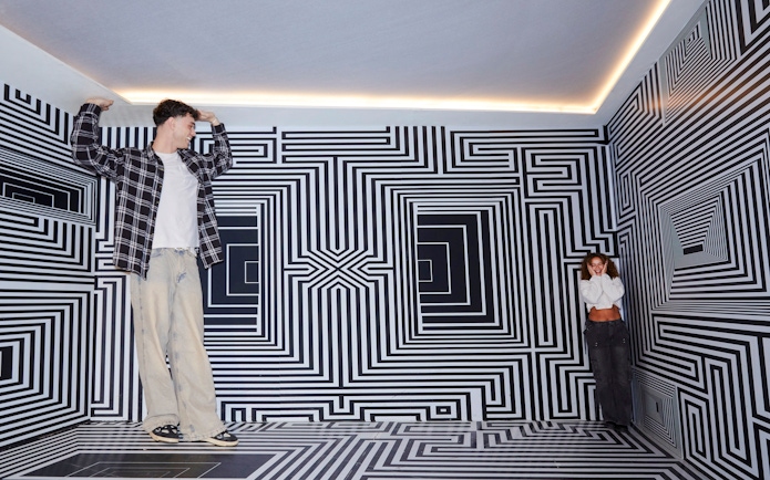 Guests exploring optical illusion room at Twist Museum, London.