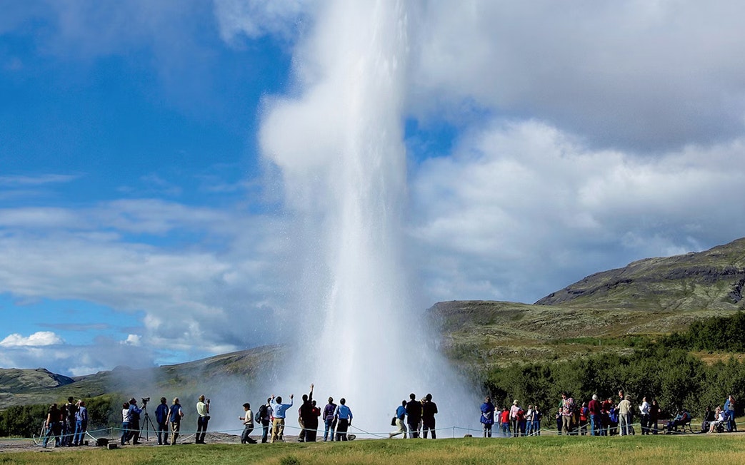 Tourists watching Geysir erupt during Golden Circle day trip in Iceland.
