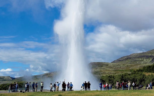 Tourists watching Geysir erupt during Golden Circle day trip in Iceland.