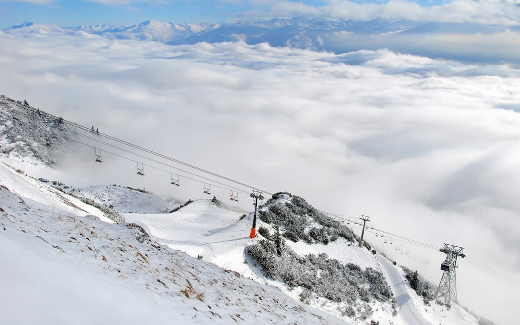 Nordkettenbahn cable car ascending snowy mountain with cloud-covered valley below.