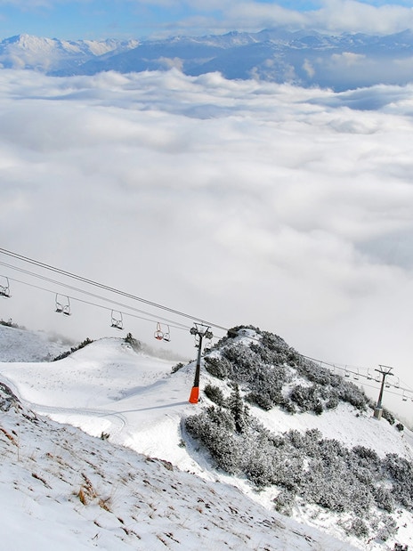 Nordkettenbahn cable car ascending snowy mountain with cloud-covered valley below.