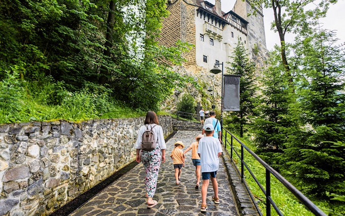 Family walking on path towards Bran Castle, Romania.
