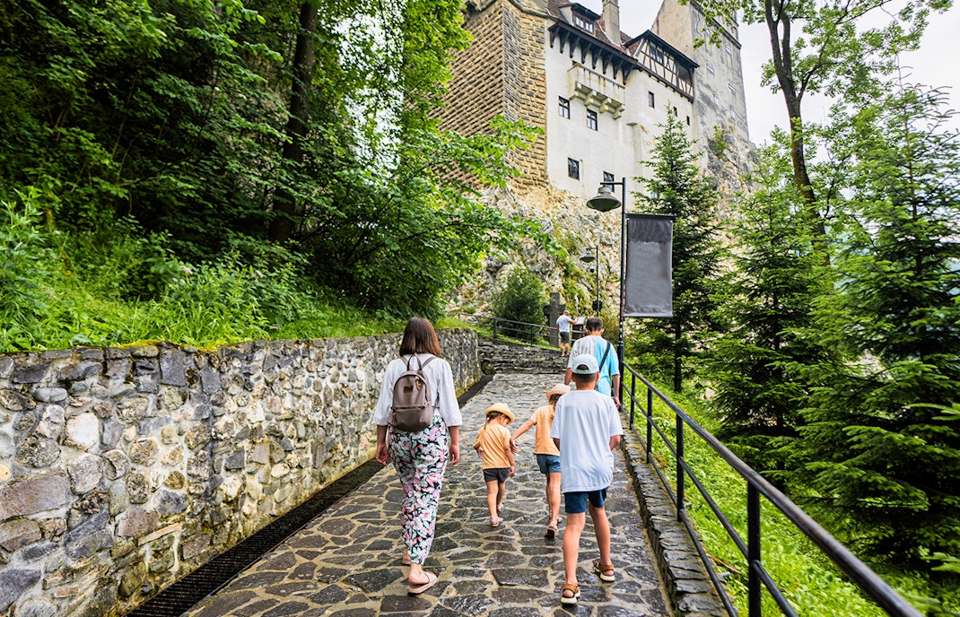Family walking on path towards Bran Castle, Romania.