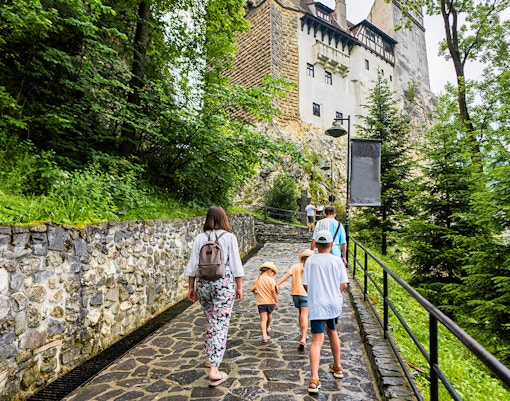 Family walking on path towards Bran Castle, Romania.
