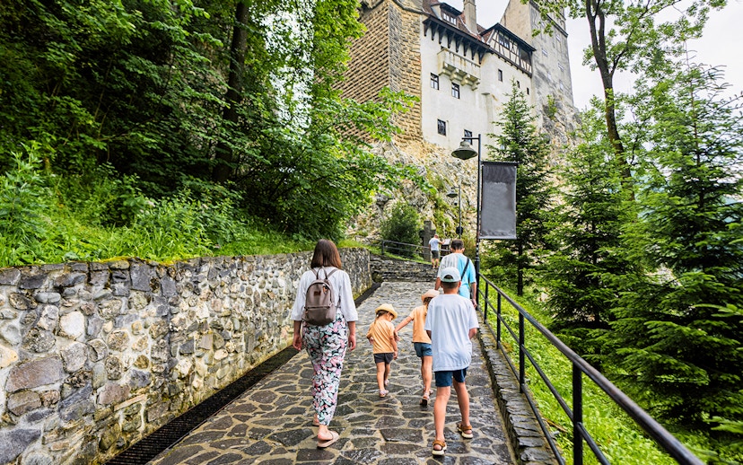 Family walking on path towards Bran Castle, Romania.