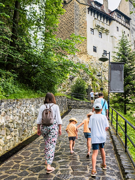 Family walking on path towards Bran Castle, Romania.