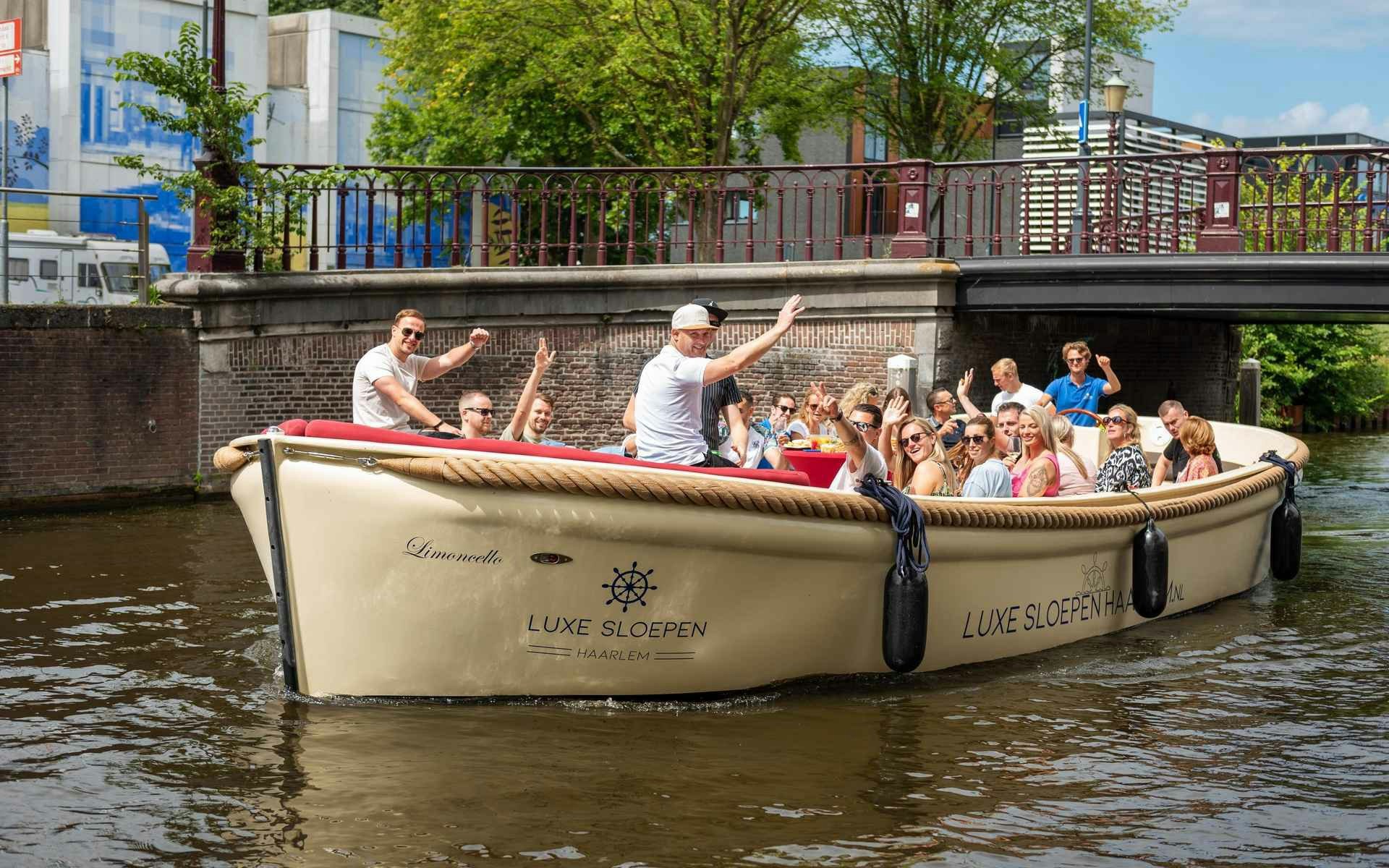 Open boat with tourists cruising a canal in Haarlem, passing under a bridge.