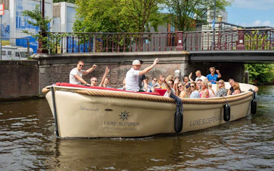 Open boat with tourists cruising a canal in Haarlem, passing under a bridge.