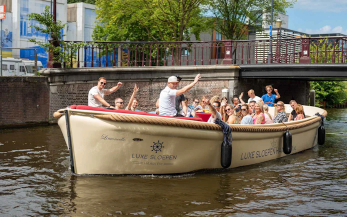 Open boat with tourists cruising a canal in Haarlem, passing under a bridge.