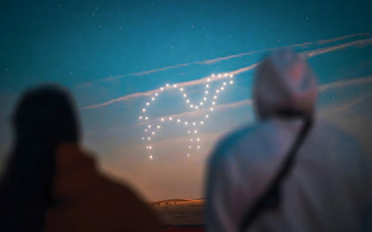 Drone light show forming a shape in the sky during a hot air balloon experience.