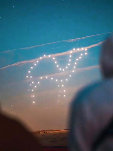Drone light show forming a shape in the sky during a hot air balloon experience.